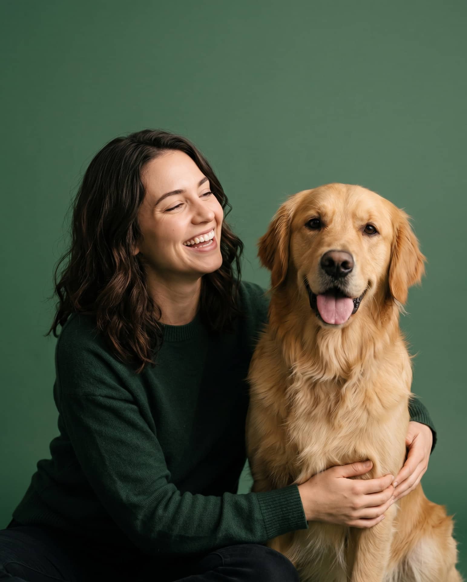 A smiling pet parent hugging her golden retriever