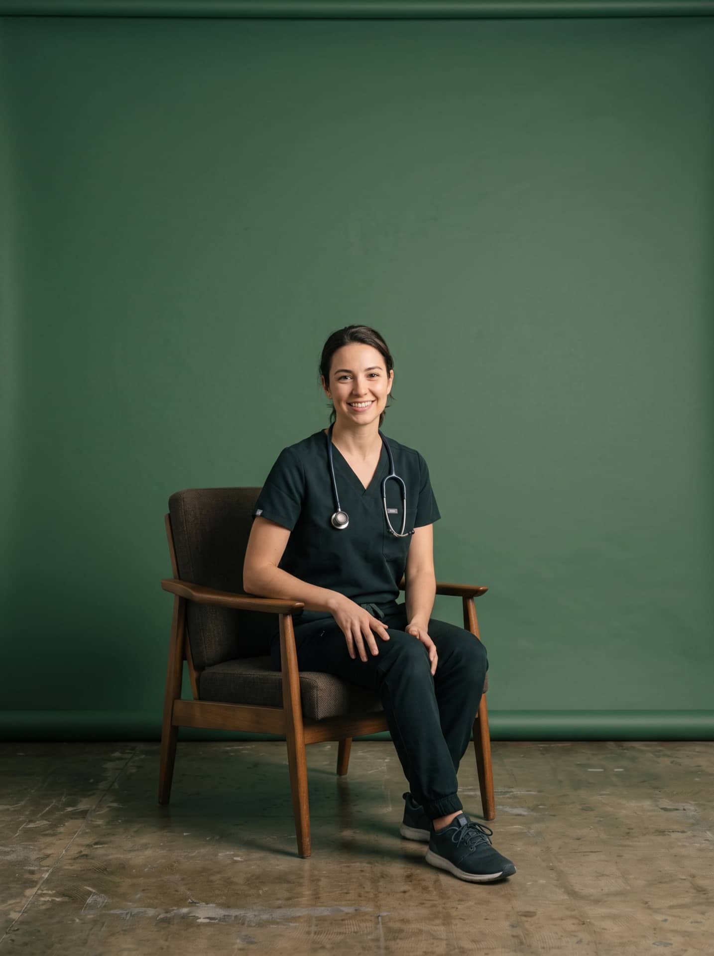 A veterinarian in scrubs smiling during a video consult